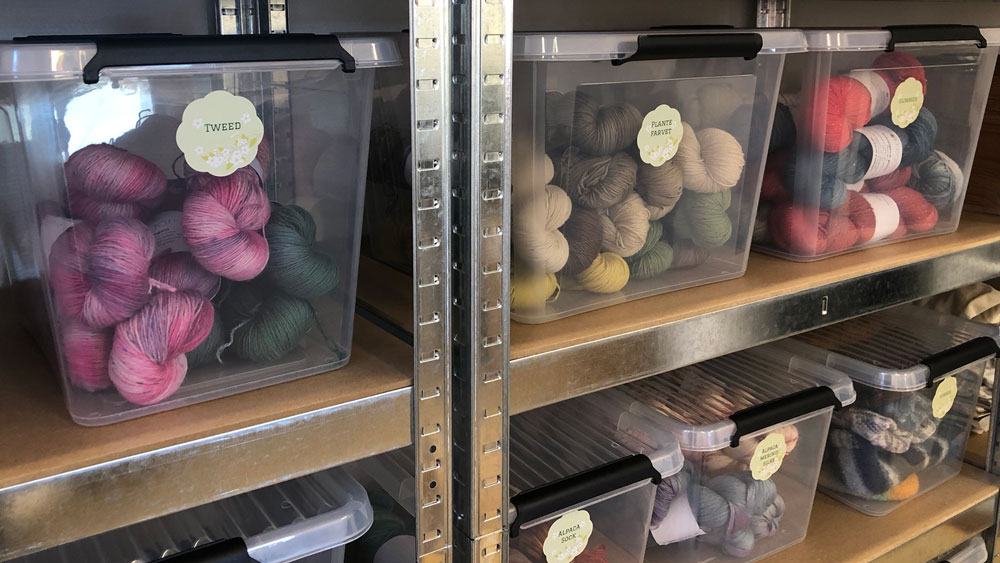 Kasser med håndfarvet garn fra Sokkegarn organiseret med blomsterformede Avery etiketter