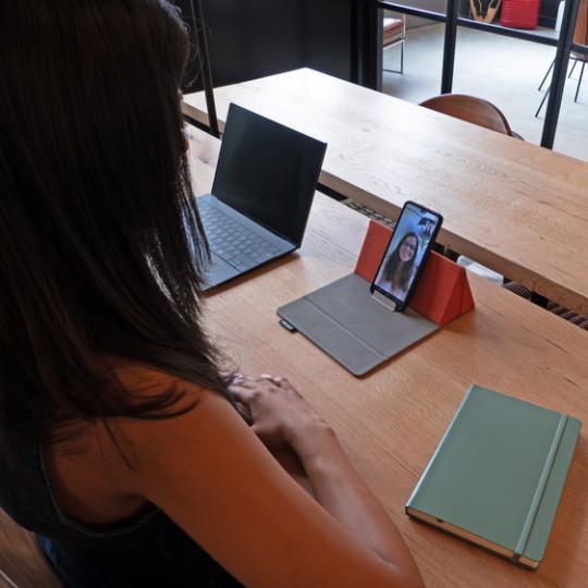 Kvinde ser på sin mobil der står i Trigo mobilholder på skrivebordet
