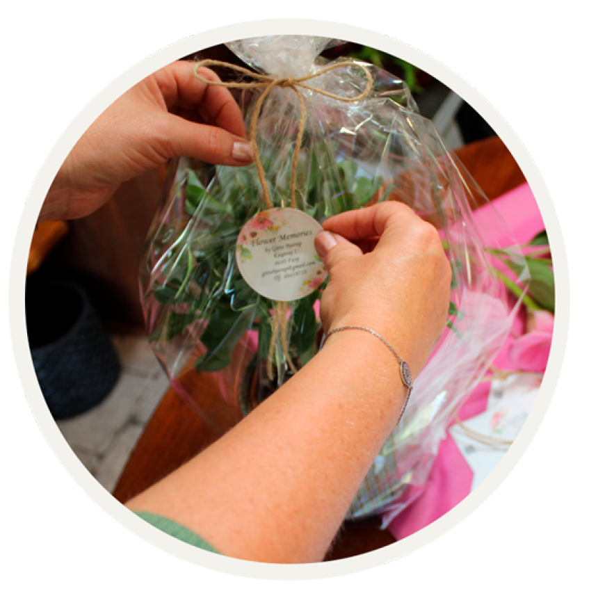 Etiket til branding af virksomheden Flower Memories, bliver sat på cellofan indpakket blomst.