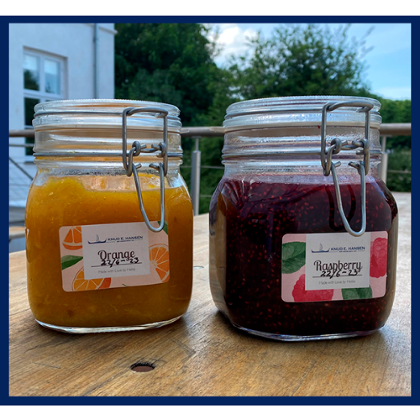 To syltetøjsglas med appelsin- og hindbærmarmelade og etiketter på hver, hvor der står Orange og Raspberry.