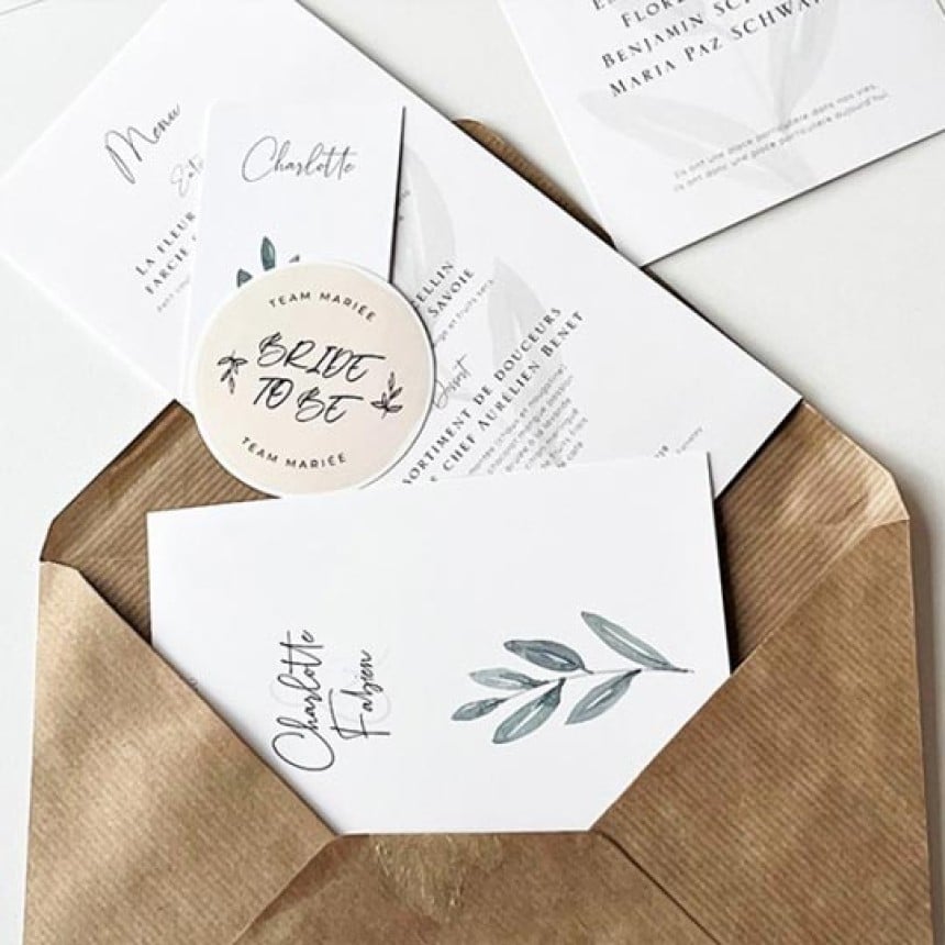 Bryllupsinvitation med botanisk design i brun kuvert og en rund sticker med teksten Bride to be.