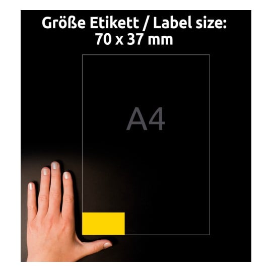 Billedet viser en hånd ved siden af en etiketstørrelse på 70 x 37 mm, med en A4-papirstørrelse angivet i baggrunden. Etiketten er fremhævet i gul.