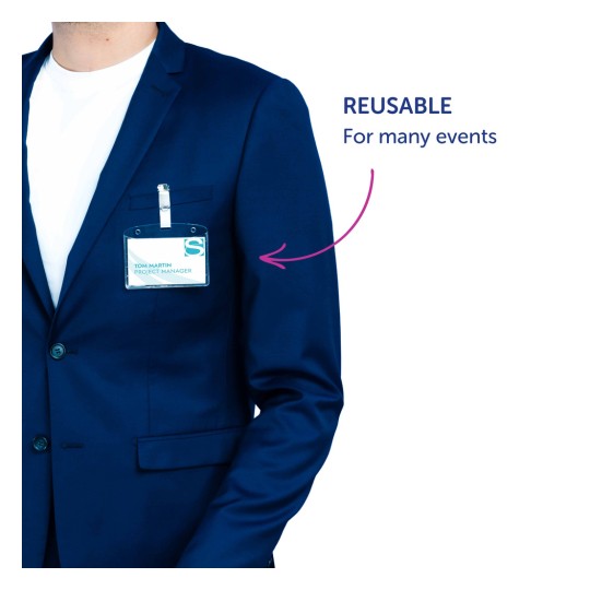 Billedet viser en person iført en marineblå blazer med en synlig navneskilt på brystet. Skiltet angiver navnet 'Tom Martin' og titlen 'Projektleder'. En annotation peger på skiltet med teksten 'GENBRUGELIG Til mange begivenheder'.