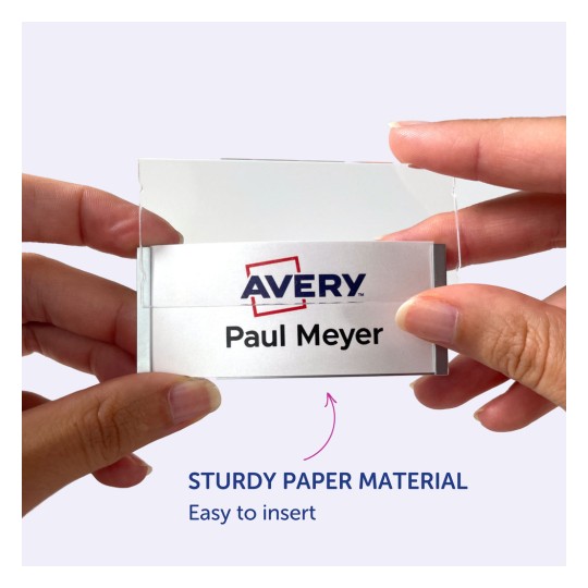 Billedet viser en person, der holder et navneskilt med navnet 'Paul Meyer' og et Avery-logo, hvilket indikerer, at det er lavet af solidt papirmateriale og er nemt at indsætte.