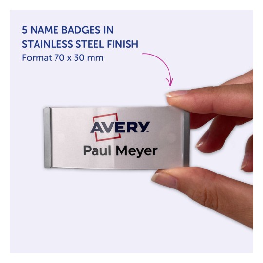 Billedet viser en person, der holder et navneskilt med teksten 'Avery Paul Meyer.' Det angiver, at produktet er et sæt med fem navneskilte i en rustfri stålfinish, måler 70 x 30 mm.
