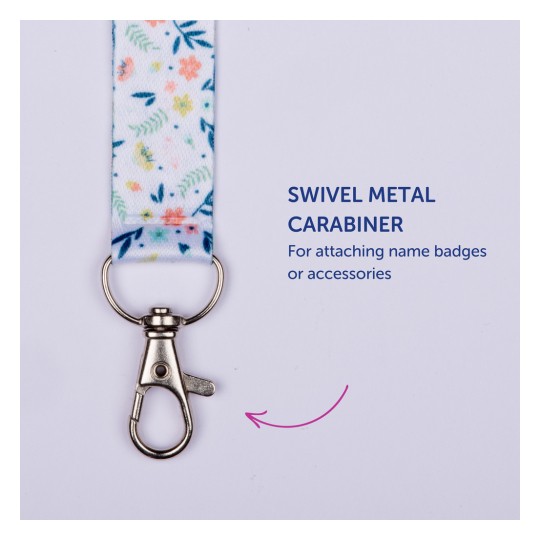 Billedet viser en farverig nøglesnor med et blomsterdesign og en drejelig metal karabinhage vedhæftet, mærket som 'Drejelig metal karabinhage til fastgørelse af navneskilte eller tilbehør'.