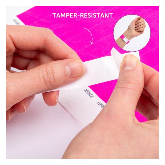 Billedet viser en persons hænder, der piller et manipulationssikkert armbånd af et ark. Baggrunden har en lys pink farve, og en mindre indsats viser armbåndet påført på et håndled.