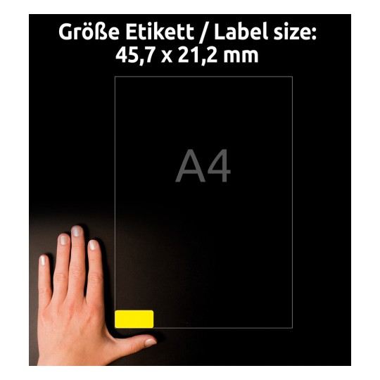 Billedet viser en hånd ved siden af et A4-papir med en etiketstørrelse på 45,7 x 21,2 mm, med en gul etiket i det nederste hjørne.