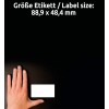 Billedet viser en hånd placeret ved siden af en tom etiket på en mørk baggrund. Etikettens dimensioner er nævnt på tysk og angiver størrelsen som 88,9 x 48,4 mm.