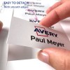 Billedet viser en hånd, der fjerner en etiket fra et ark, med navnet 'Paul Meyer' og 'Avery' logoet, samt en note, der angiver, at det er nemt at fjerne med jævne kanter.
