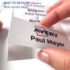 Billedet viser en hånd, der holder et navneskilt, hvorpå der står 'Avery Paul Meyer.' Det fremhæver, hvor let det er at fjerne skiltet og understreger de glatte kanter.