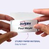 Billedet viser en person, der holder et navneskilt med Avery-logoet og navnet 'Paul Meyer' på det. Navneskiltet ser ud til at være let at indsætte i en holder lavet af robust papirmateriale.