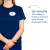 Billedet viser en person iført en marineblå skjorte med et navneskilt, der læser 'B. Carlos, Marketing Director.' Ved siden af dem er der tekst, der beskriver en selvklæbende funktion, der klæber til tøj og let kan fjernes uden at efterlade rester.