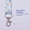 Billedet viser en farverig nøglesnor med et blomsterdesign og en drejelig metal karabinhage vedhæftet, mærket som 'Drejelig metal karabinhage til fastgørelse af navneskilte eller tilbehør'.