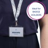 Billedet viser en person iført en mørk skjorte med en nøglesnor, der viser en ID-badge med teksten 'MELINA DOPPER' og 'Designer.' Nøglesnoren har et farverigt blomster mønster. En taleboble på billedet siger 'Ideel til ID-KORTHOLDERE.'