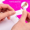 Billedet viser en persons hænder, der piller et manipulationssikkert armbånd af et ark. Baggrunden har en lys pink farve, og en mindre indsats viser armbåndet påført på et håndled.