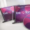 Billedet viser to CD-etuier med titlen 'Sales Meeting' og en disc med et farverigt design. Designet indeholder cirkler i nuancer af pink og lilla, sammen med teksten 'beEven.'